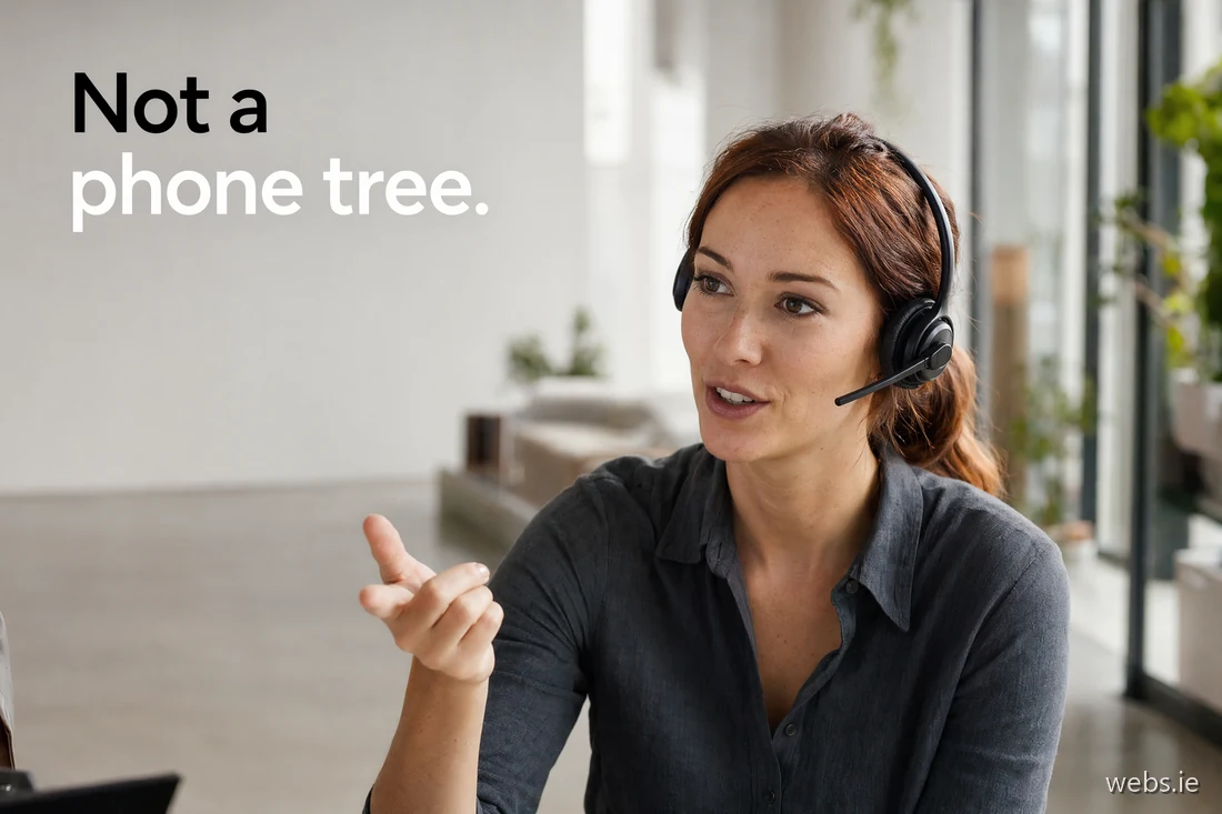 European woman in her early thirties on a professional headset mid-conversation at a sleek studio standing desk, one hand raised in a precise indexing gesture
