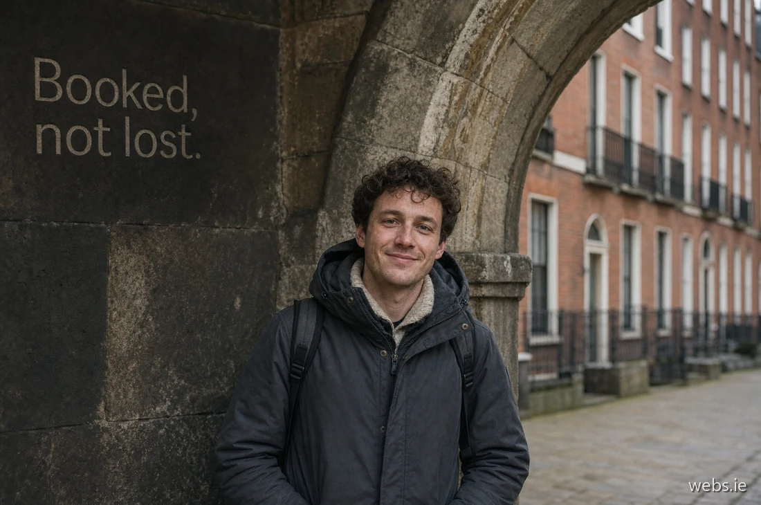 Young European man under a Dublin stone archway reads an SMS appointment confirmation on his phone, a small genuine smile of relief